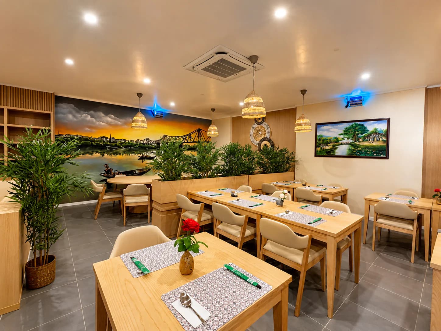 Sala do restaurante Hà Nội Xưa em Lisboa, com vegetação e um mural de Hanói